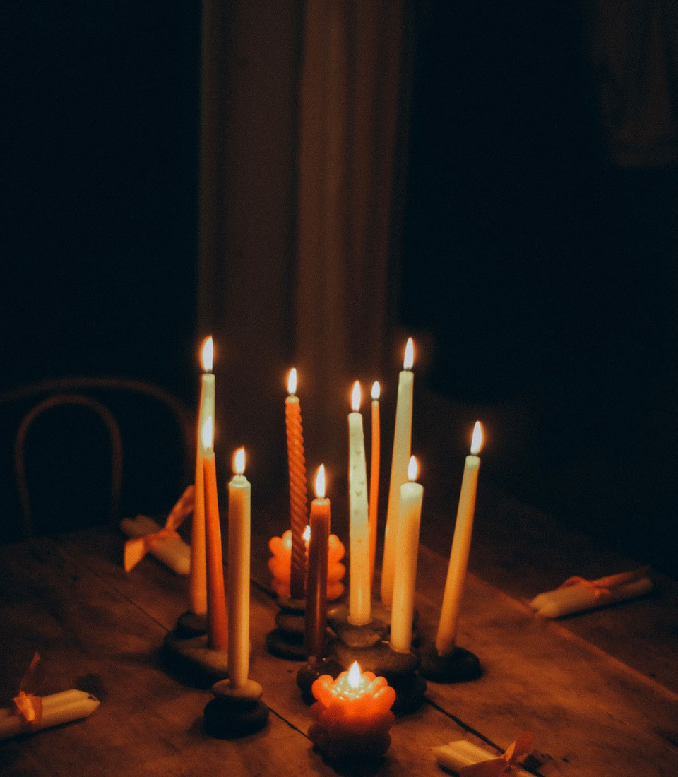 Candles glowing on a wooden table in a dim, cozy room (illustrative photograph)