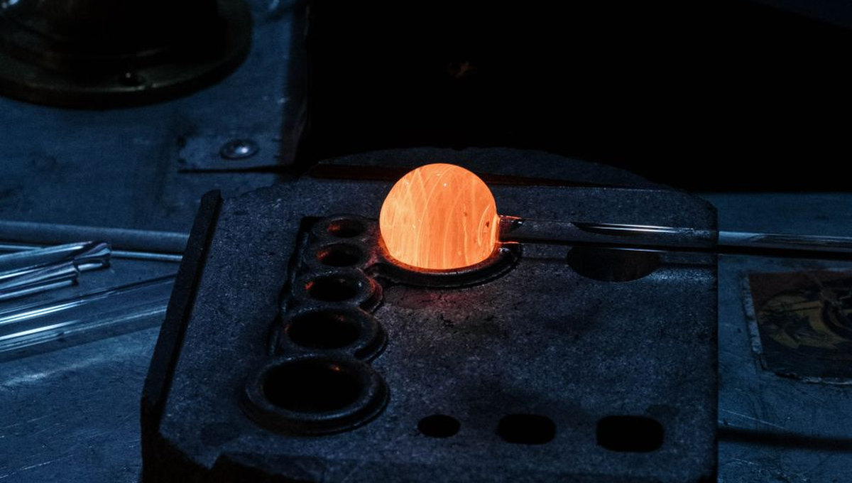 Glowing molten glass sphere on a workbench (illustrative stock photo)